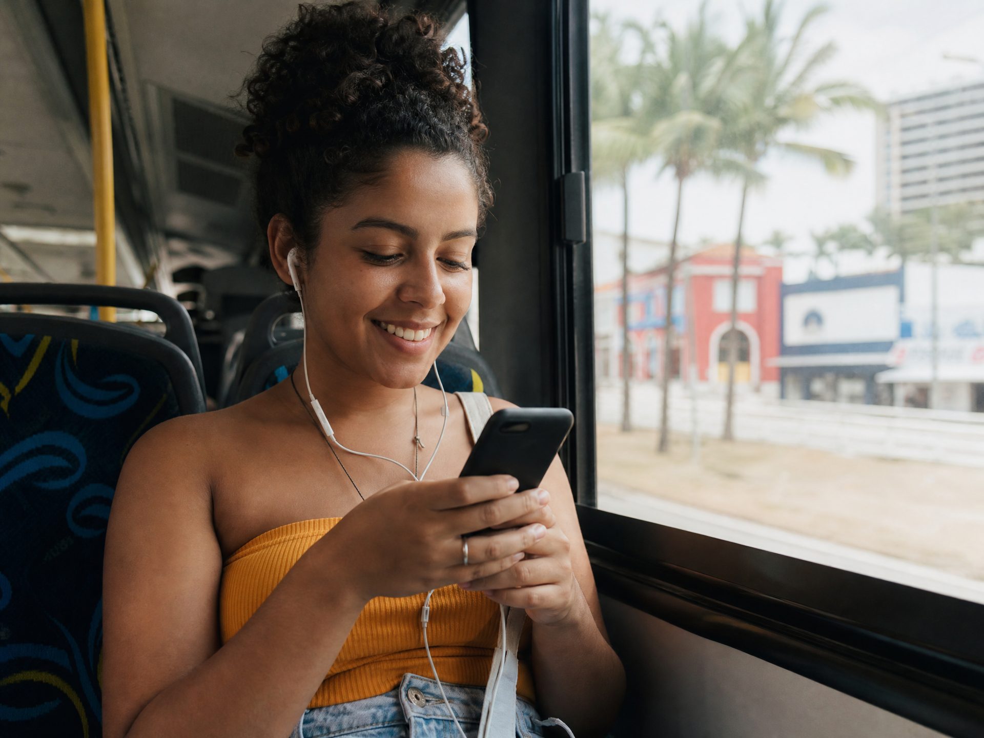 Jovem usando celular no ônibus